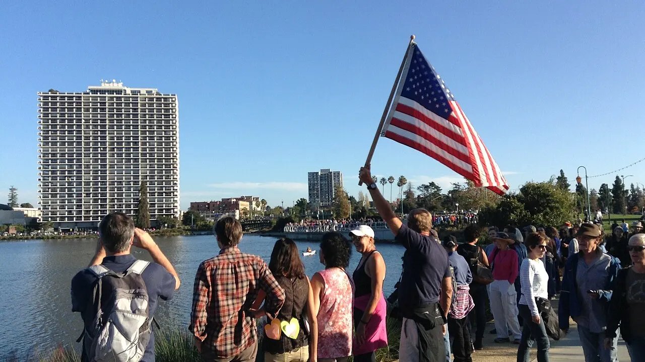 A man raises an American flag at Lake Merritt in Oakland
