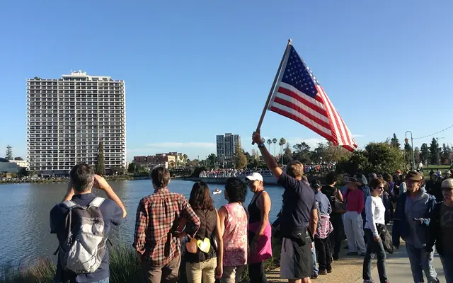 A man raises an American flag at Lake Merritt in Oakland